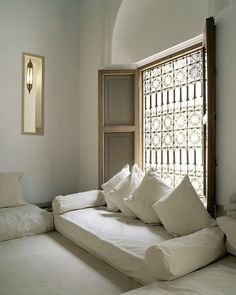 a bed with white pillows in front of a window