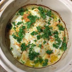 an omelet in a white bowl with parsley on top