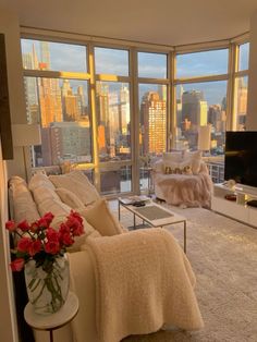 a living room filled with furniture and large windows overlooking the cityscape in the distance