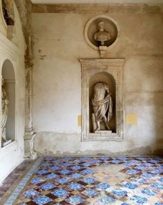 an old room with a statue on the wall and tiled floor in front of it