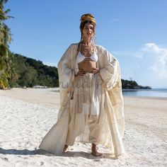 a woman standing on top of a sandy beach next to the ocean and palm trees