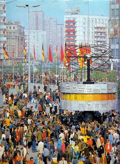 a large group of people standing in front of buildings with flags on the top of them