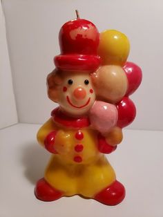 a ceramic figurine with an apple on it's head, holding two balloons