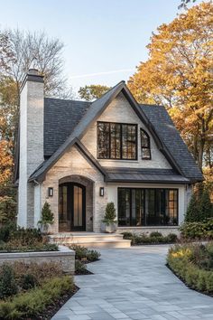 a white brick house with black windows and stone walkway leading to the front door area