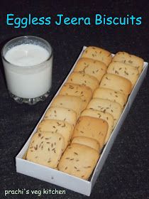 eggless jeera biscuits in a box next to a glass of milk