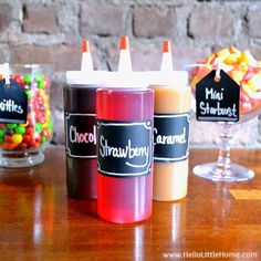 three different flavors of liquid sitting on top of a wooden table next to a glass filled with candy