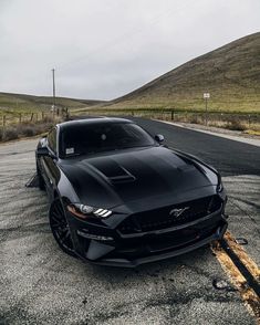 a black mustang parked on the side of the road