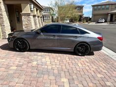 a silver car parked on the side of a road next to a brick walkway and house