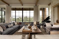 a living room filled with furniture and a grand piano in front of two large windows