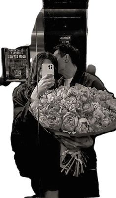 a man and woman kissing in front of a parking meter while holding a bouquet of flowers