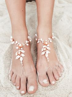 a woman's feet wearing barefoot sandals with pearls and leaves on the toenails