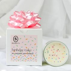 a birthday cake candle in a box next to a container with sprinkles