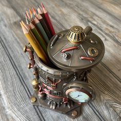 a clock with many different colored pencils in it on a wooden table next to a pair of scissors