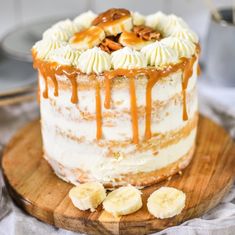 a cake with bananas and caramel drizzled on top, sitting on a wooden platter