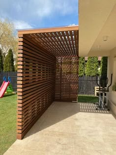 an outdoor play area with a slide and wooden slatted privacy wall on the side