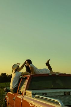 two people sitting on the back of a pickup truck with their feet up in the air