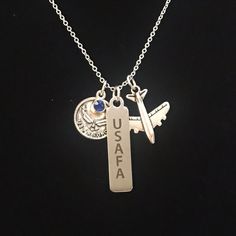 This sliver tone necklace has charms depicting the Air Force wings emblem with a blue gem, a laser engraved "USAFA" stainless steel charm and an airplane.* 19" Stainless Steel chain Air Force Uniform, Air Force Symbol, Air Force Basic Training, Air Force Uniforms, Mom Challenge, Army Mom Shirts, Air Force Mom, Marine Mom, Military Mom