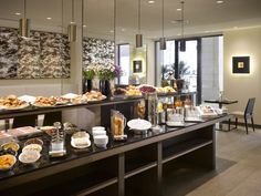 a buffet area with various foods and drinks on the counter in front of large windows