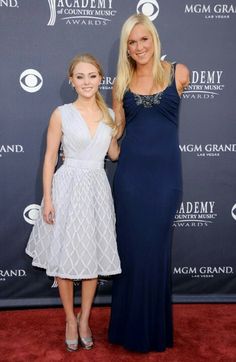 two women standing next to each other on a red carpet