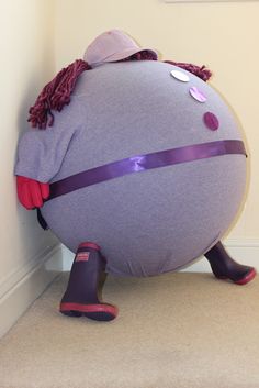 a giant purple ball sitting next to a wall with a pair of rubber boots on it