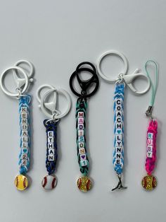 four keychains with different designs on them sitting next to each other in the shape of baseballs