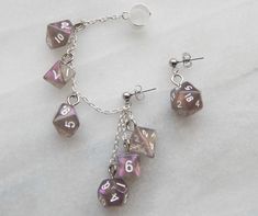 🎲 Carry your love of gaming with you wherever you go when you wear these mini supervolcano stardust purple & orange polyhedral dice chained ear cuffs! All seven polyhedral dice are present on the chain and dangling from the posts. These are the perfect fancy and funky accessory for game night, cons, or wherever you feel like showing off your love of gaming and dice. This is a mismatched set with a cuff designed for the right ear (but can be worn on the left as well) with six dice and a post for Dnd Jewelry, Geek Aesthetic, Ear Cuff Chain, Aesthetic Earrings, Jewelry Ear, Ear Climber, Wrap Earrings, Polyhedral Dice, Ear Climbers