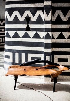 a wooden bench sitting in front of a black and white wall with geometric designs on it