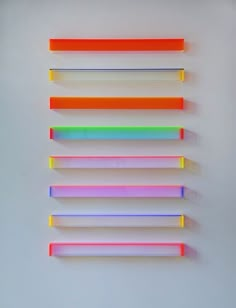 several different colored toothbrushes lined up against a white wall with no one in it