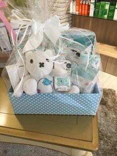 a teddy bear and other items in a blue gift box on a table with white polka dots