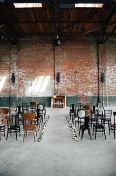 an empty room with many chairs and tables set up for a wedding ceremony in front of a brick wall