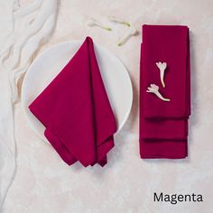 a white plate topped with red napkins next to a purple flower on a table