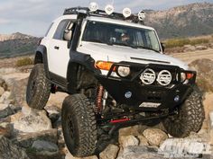 a white four - doored off road vehicle driving on rocks