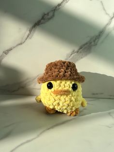 a small stuffed animal with a hat on it's head sitting in front of a marble wall