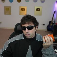 a man wearing sunglasses and holding an orange object