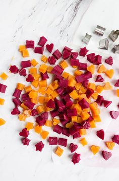 chopped up beets and carrots on a white counter top with cutters next to them