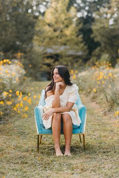 a woman sitting on a blue chair in the grass