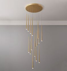 a gold chandelier hanging from the ceiling in a room with gray walls and flooring