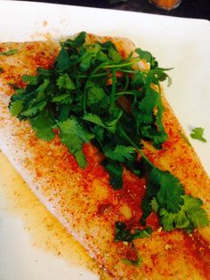 a white plate topped with fish covered in cilantro