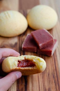 a person holding a piece of bread with meat in it on a wooden cutting board