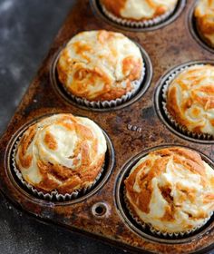 a muffin tin filled with orange and white cupcakes covered in icing