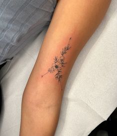 a woman's arm with a small flower tattoo on it