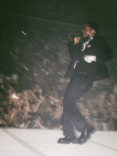 a man standing on top of a stage holding a microphone in front of a crowd