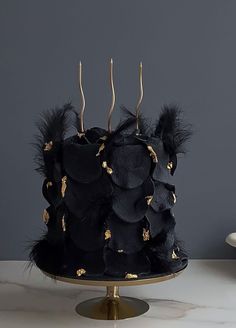 a black cake with gold decorations and feathers