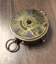 an antique brass pocket watch on a wooden table with keyring in the foreground