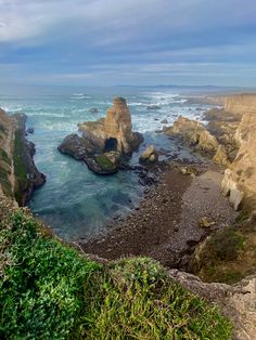 an ocean view looking down at the rocky coastline and cliffs with green vegetation on either side