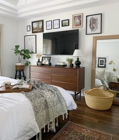 a bedroom with a bed, dresser and television on the wall next to a window