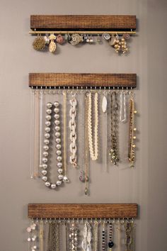 several necklaces are hanging on the wall next to two wooden shelves with glass beads