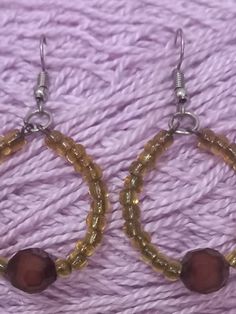 the earrings are made from glass beads and wood beaded with metal hooks on a purple background