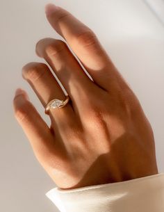 a woman's hand with a diamond ring on her left hand, against a white background