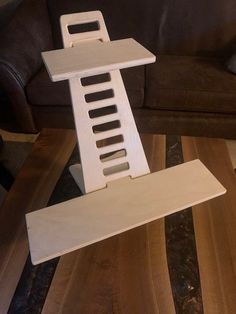 a white wooden stand sitting on top of a hard wood floor next to a couch